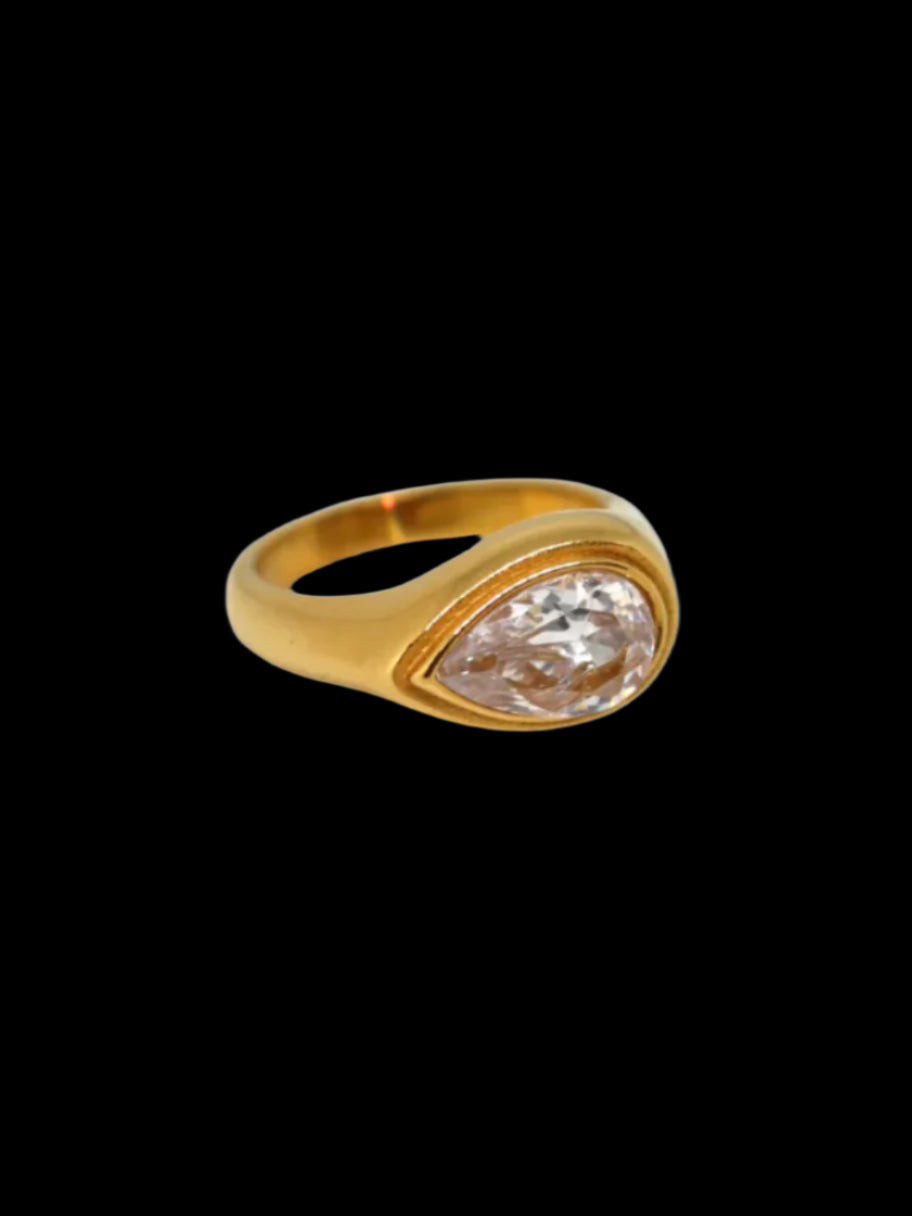 A gold-colored ring with a large solitaire diamond in the center, displayed against a black background.