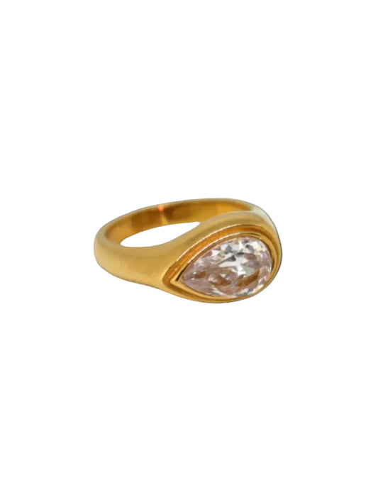 A gold-colored ring with a large solitaire diamond in the center, displayed against a black background.