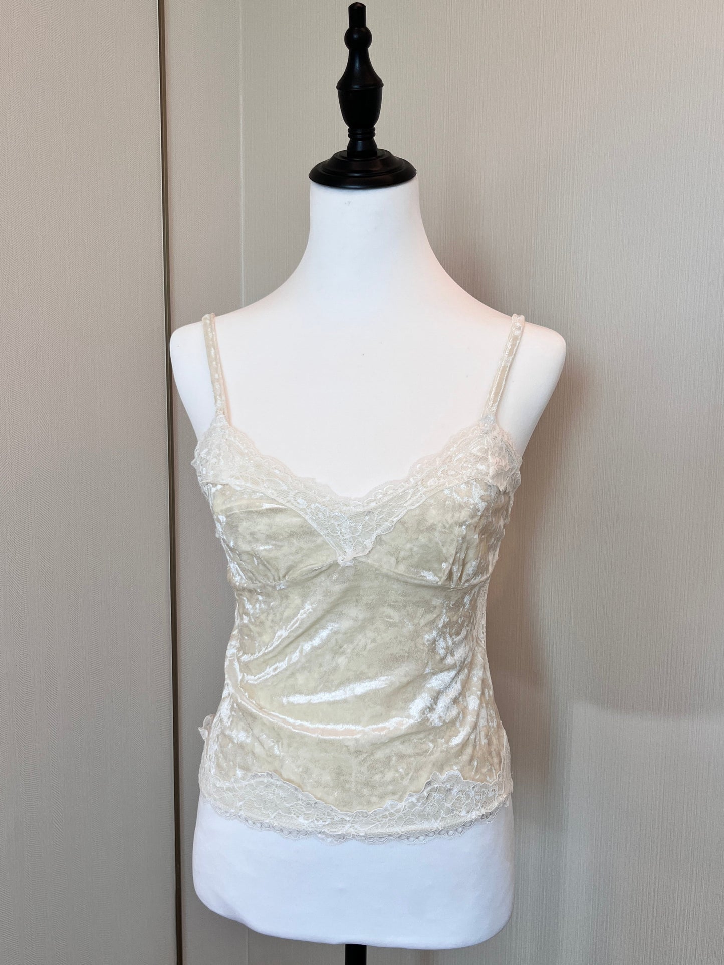 White lace top on a mannequin against a plain background