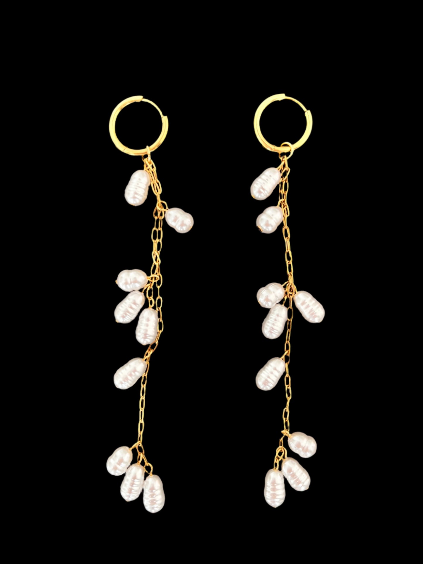 Pair of gold earrings with pearl-like beads on a black background