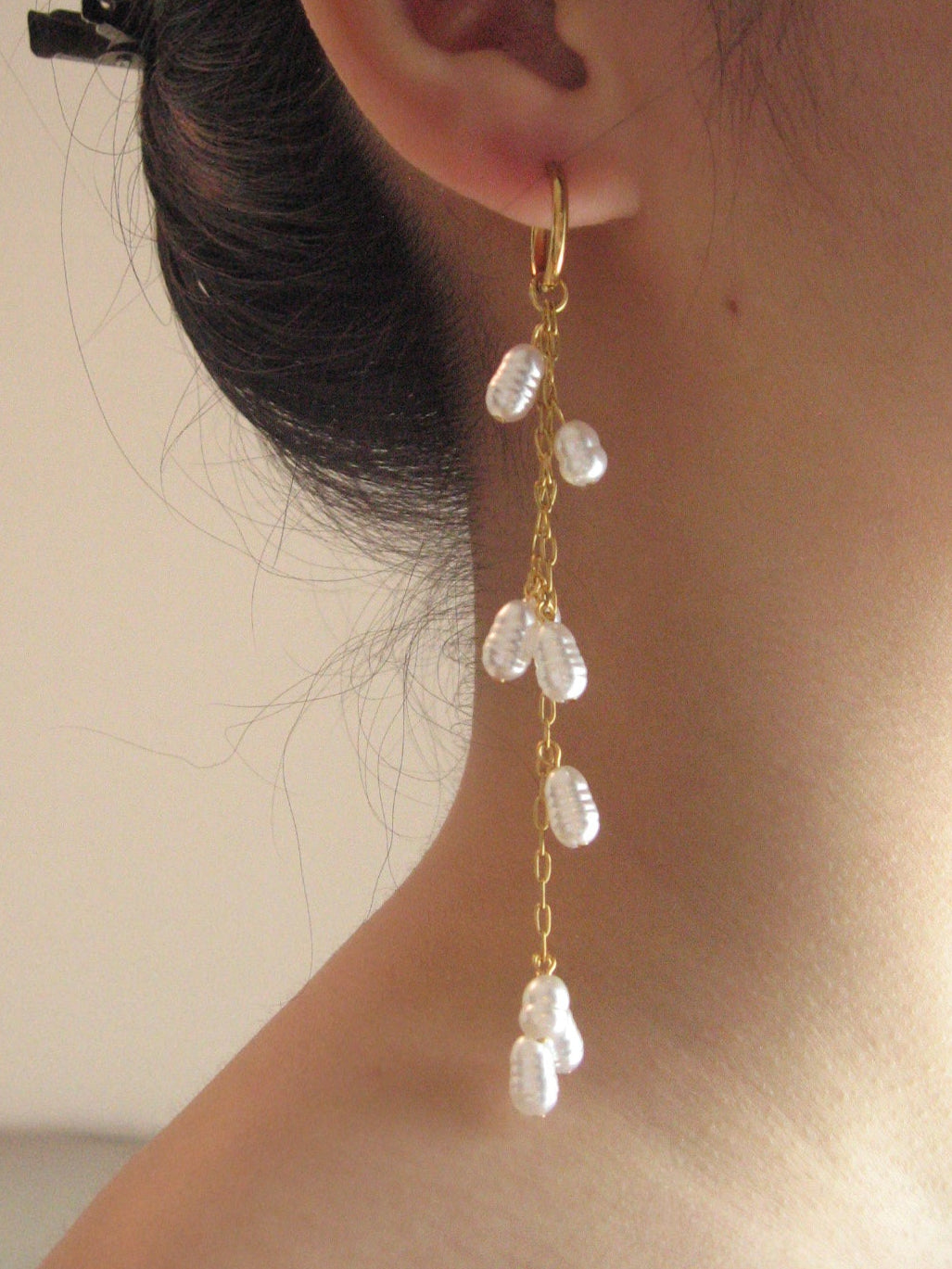 Pearl earring worn by a person with a neutral background