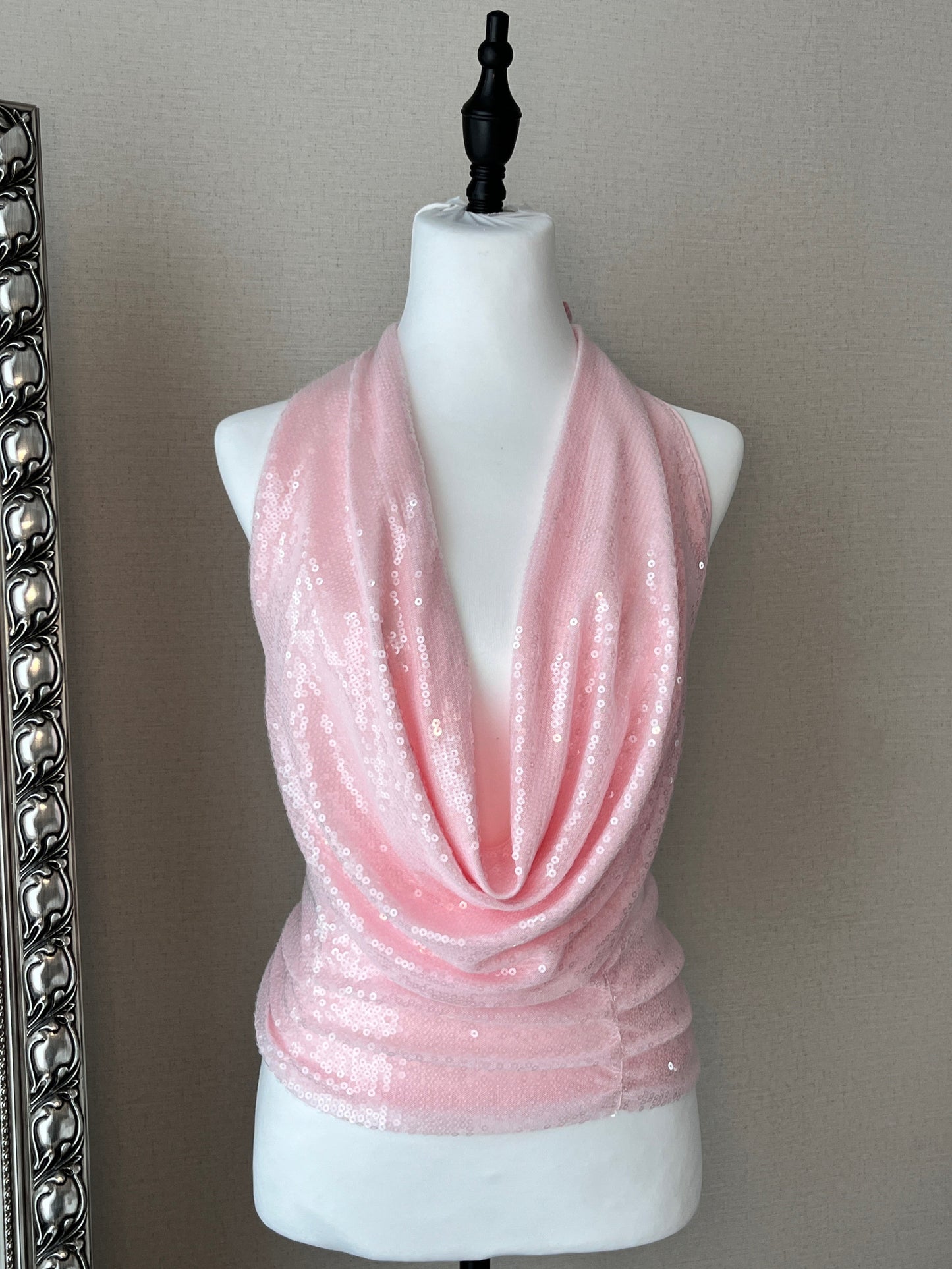 Pink sequin top on a mannequin against a beige wall.