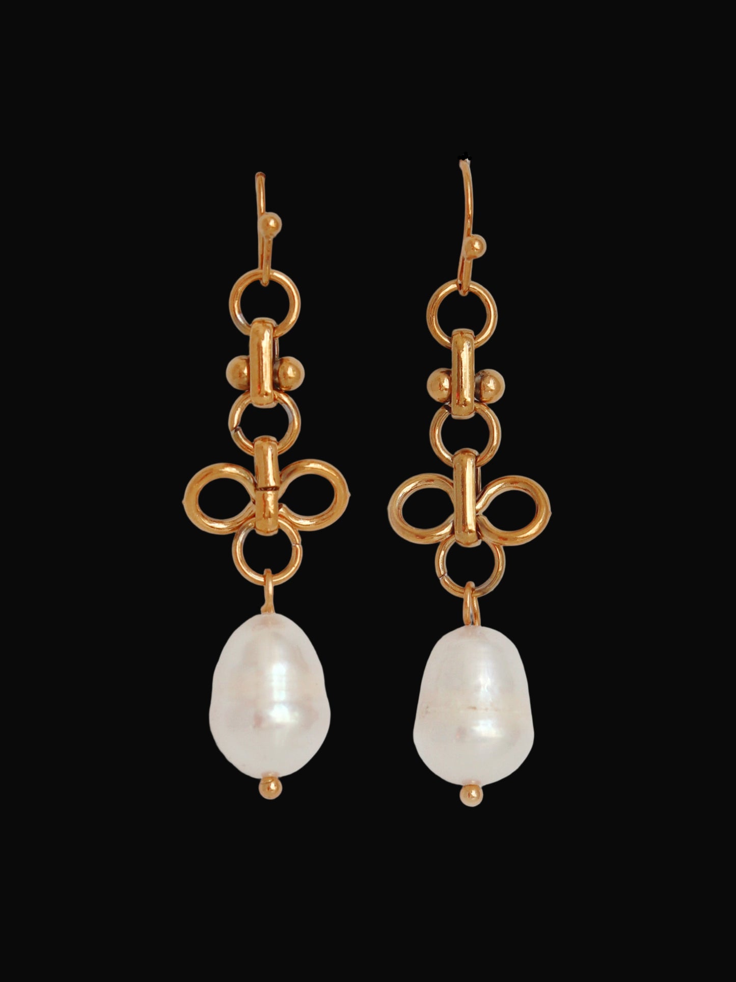 Gold bow-shaped earrings with pearl drops on a light gray background
