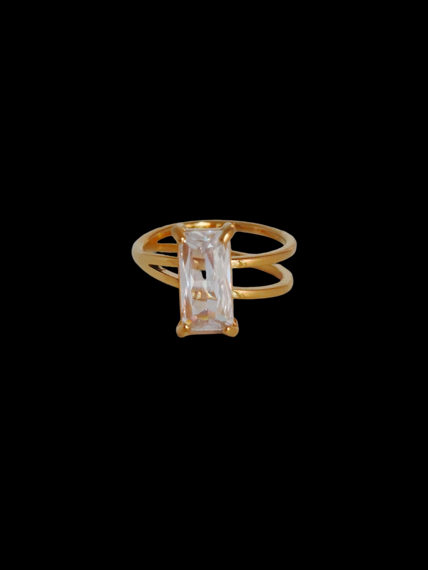 Gold ring with a clear gemstone on a light gray background