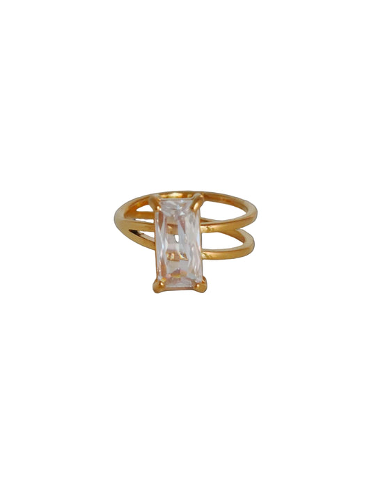 Gold ring with a clear gemstone on a light gray background
