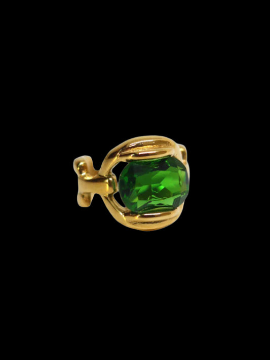 A gold-colored band ring with a large green emerald-like stone set in the center.