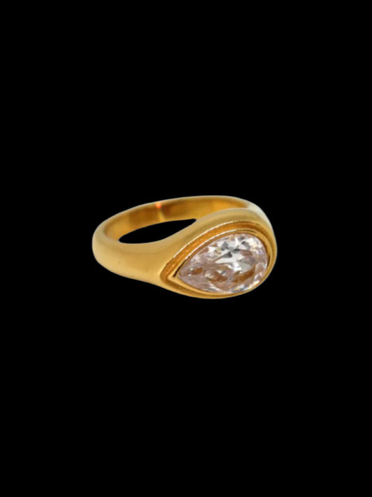 A gold-colored ring with a large solitaire diamond in the center, displayed against a black background.
