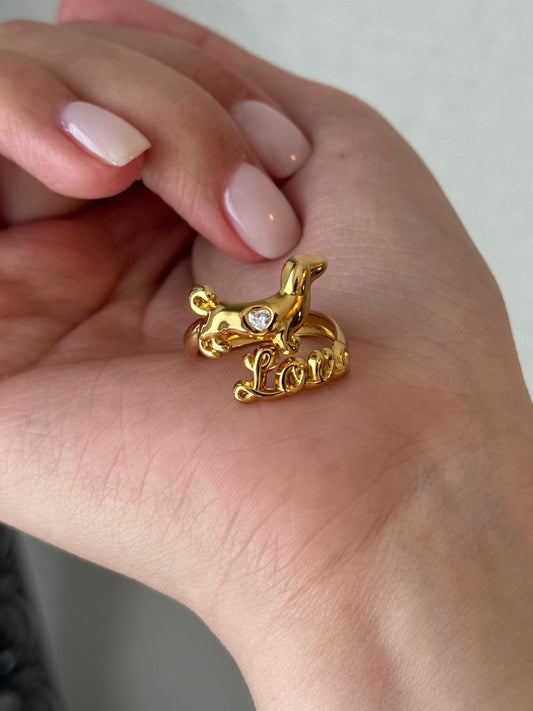Gold ring with a small animal design on a hand against a neutral background