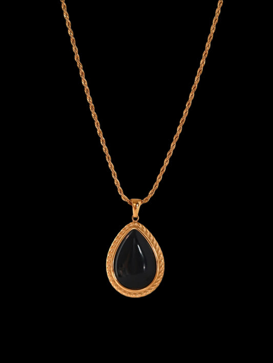 Necklace with a black teardrop pendant on a gold chain against a white background
