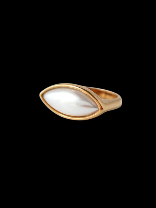Gold ring with a white stone on a light gray background