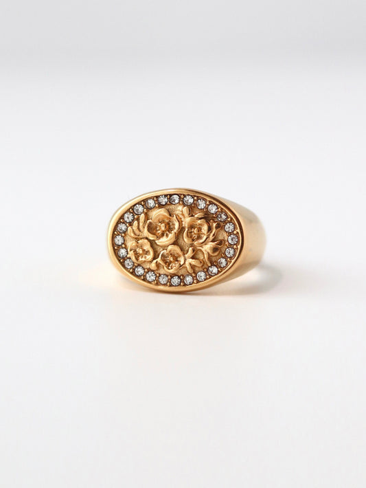 Gold ring with floral design and small stones on a white background