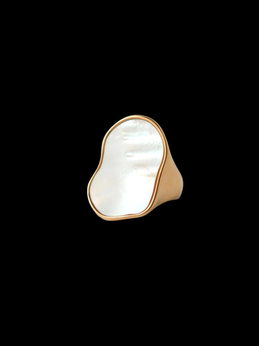 Gold ring with a large white stone on a gray background