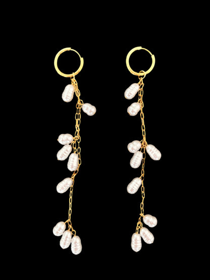 Pair of gold earrings with pearl-like beads on a black background
