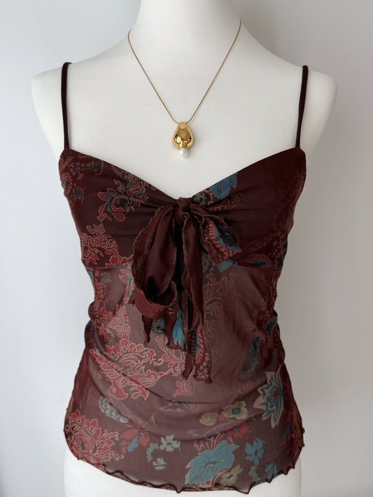 Brown patterned top on a mannequin with a gold necklace against a white background
