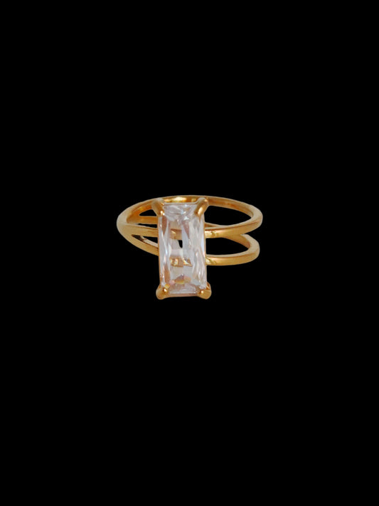 Gold ring with a clear gemstone on a light gray background