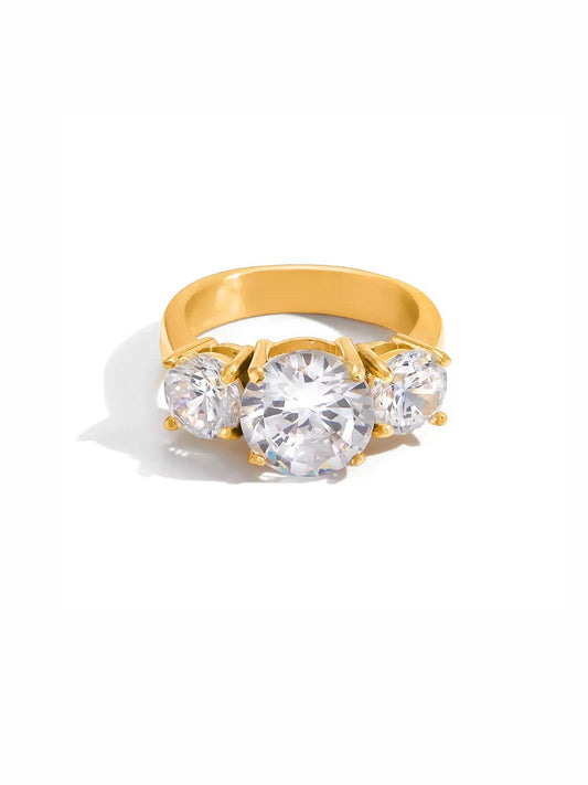 Gold ring with three clear gemstones on a white background