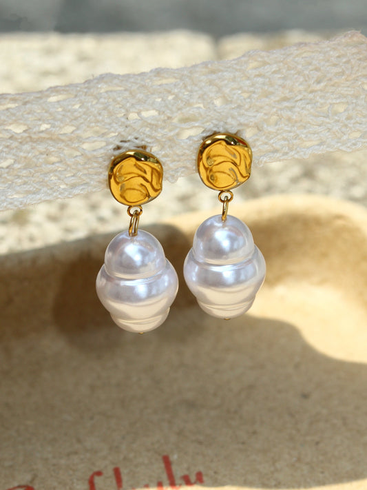 Pearl earrings with gold posts on a textured surface