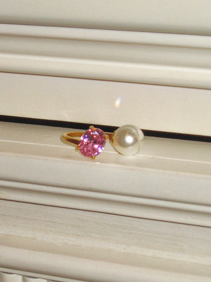 Ring with pink gemstone and pearl on a textured surface