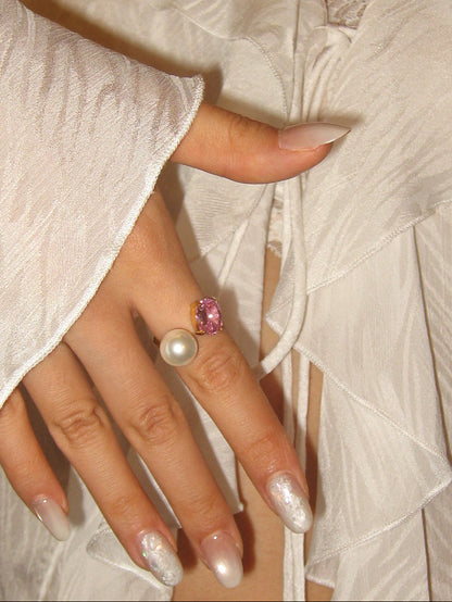 Close-up of a hand wearing two rings with a white garment in the background