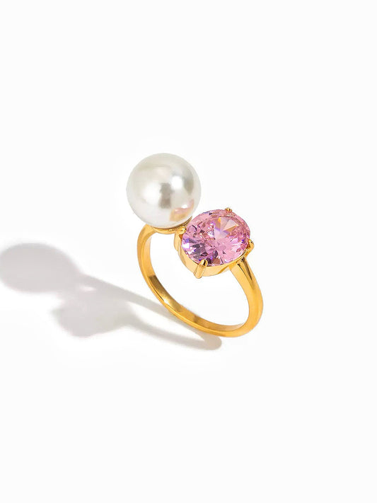 Gold ring with a pink gemstone and pearl on a white background